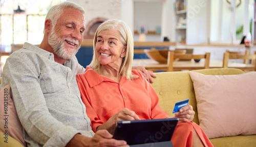 Retired Senior Couple At Home With Digital Tablet Making Purchase Or Booking Using Credit Card © Monkey Business