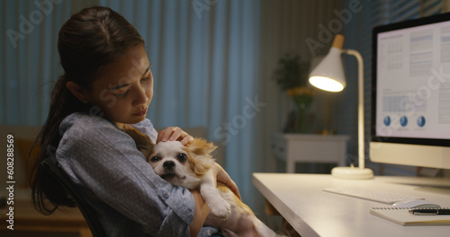 Young asia single woman remote work late night at home office workspace hug kiss cute sleepy chihuahua dog. Pet as child millennial lifestyle. Small animal puppy stress relief therapy for workforce. © ChayTee