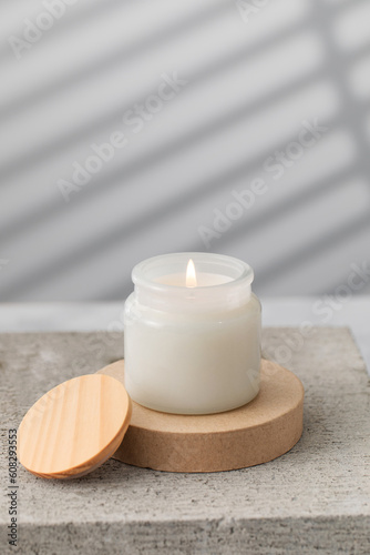 A burning white interior candle in a glass cup. The concept of home decor, comfort. Handmade candle