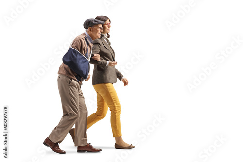 Young woman holding a senior with an injured arm and walking together