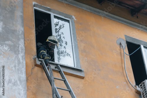 View of a brave firefighter in a protective uniform. Rescuer in protective gear. Firefighters put out a fire in a residential building.