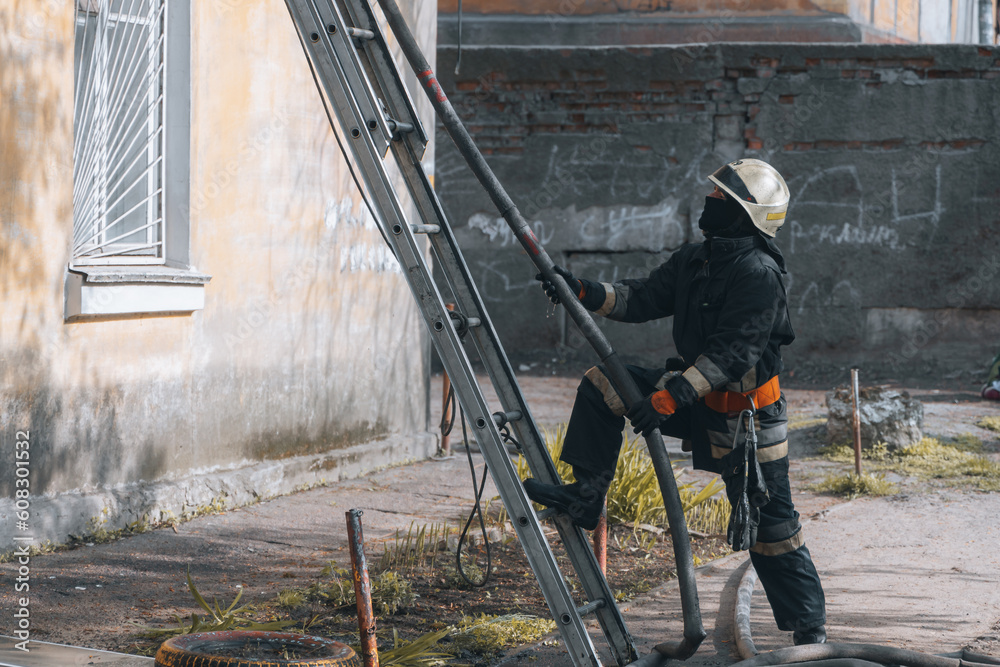 View of a brave firefighter in a protective uniform. Rescuer in protective gear. Firefighters put out a fire in a residential building. View of a brave firefighter in a protective uniform. Rescuer in protective gear. Firefighters put out a fire in a residential building.