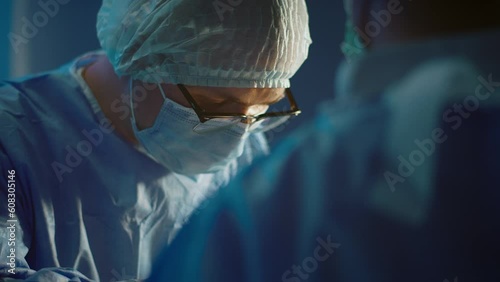 A close up shot of the surgeon wearing glasses and concentrating performing a surgery in a medical room photo