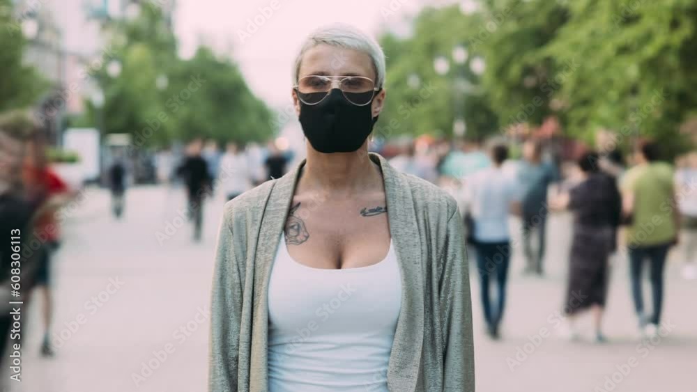 Zoom-in time lapse portrait of young woman in facial mask standing outdoors in city surviving pandemic. Healthcare and individual protection concept. Zoom-in time lapse portrait of young woman in facial mask standing outdoors in city surviving pandemic. Healthcare and individual protection concept.