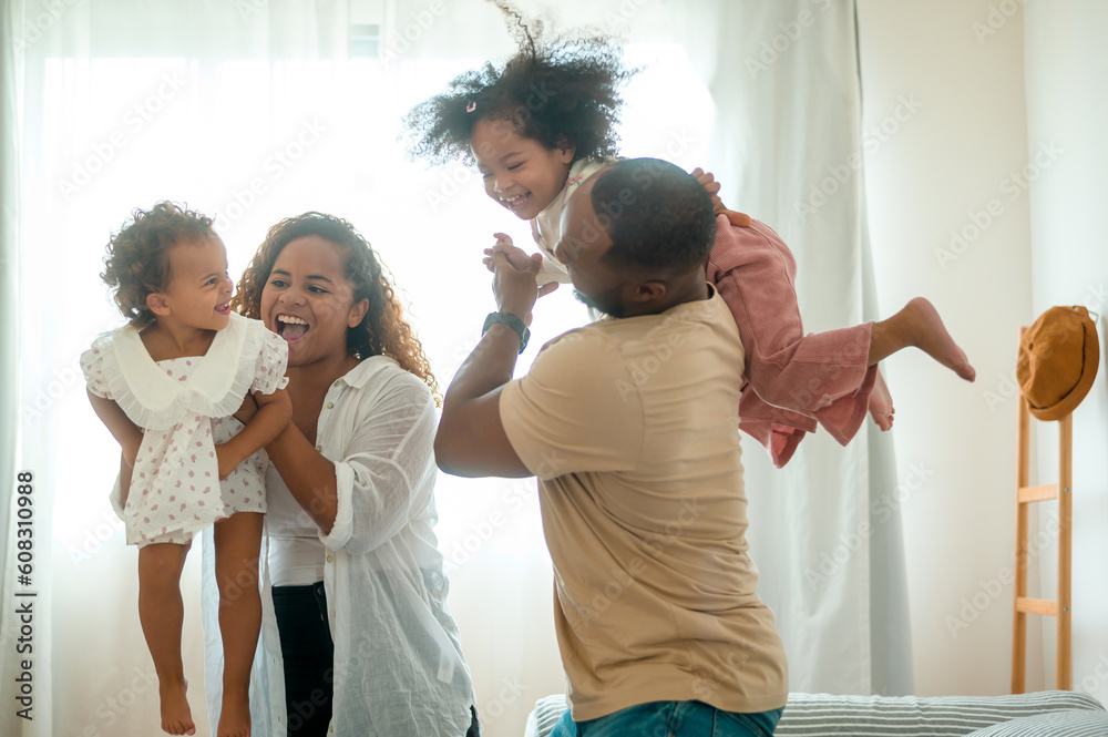 Happy African American Parents with little daughters playing on the bed in bedroom at home, happy family concept Happy African American Parents with little daughters playing on the bed in bedroom at home, happy family concept