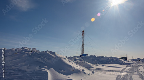 The Northern gas field. There is a lot of snow in the foreground. In the background is a mobile installation for well repair. A frosty winter day. Sunny blue sky