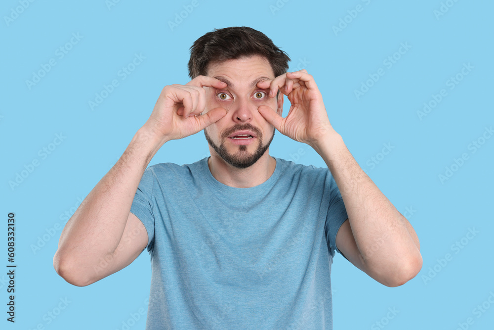 Tired man on light blue background. Insomnia problem