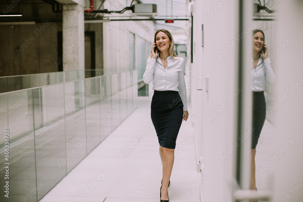 Obraz premium Young business woman using mobile phone in the office hallway