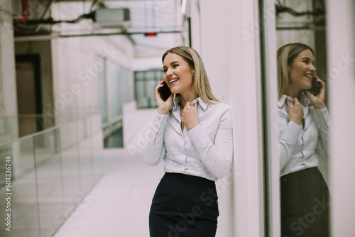 Young business woman using mobile phone in the office hallway © BGStock72