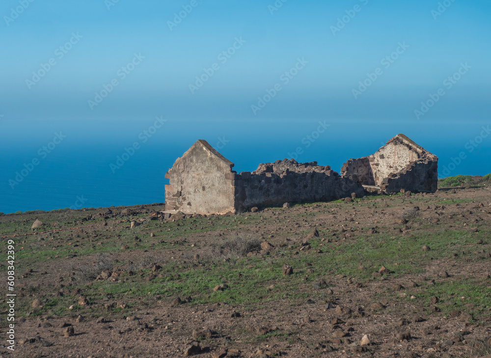 Abandoned ruins of farm house at flat plateau on top of La Merica mountain with cacti, stones and sea view. valle Gran Rey, La Gomera, Canary Islands. Copy space. Abandoned ruins of farm house at flat plateau on top of La Merica mountain with cacti, stones and sea view. valle Gran Rey, La Gomera, Canary Islands. Copy space.