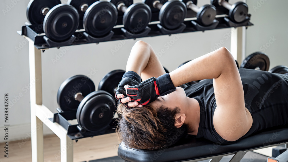 Asian Sport man with well trained body in black sportswear lying on workout bench preparing to do sit-up in fitness gym, warming up before weight training. Bodybuilding concept Asian Sport man with well trained body in black sportswear lying on workout bench preparing to do sit-up in fitness gym, warming up before weight training. Bodybuilding concept