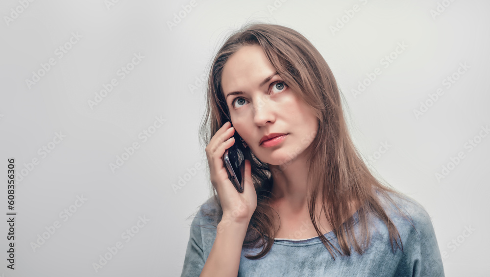 An attractive woman speaks on the phone, an isolate on a light background. An attractive woman speaks on the phone, an isolate on a light background.