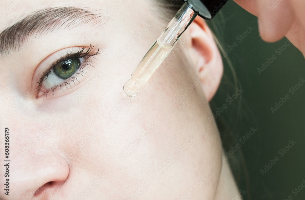 Close-up portrait of woman applying glass peep liquid, skin texture. Apply a tea tree moisturizing serum to your face.