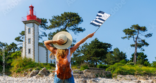 tourism in Brittany- Lighthouse on atlantic coast and woman tourist holding breton flag- Brittany in France (phare de Sainte Marine) photo