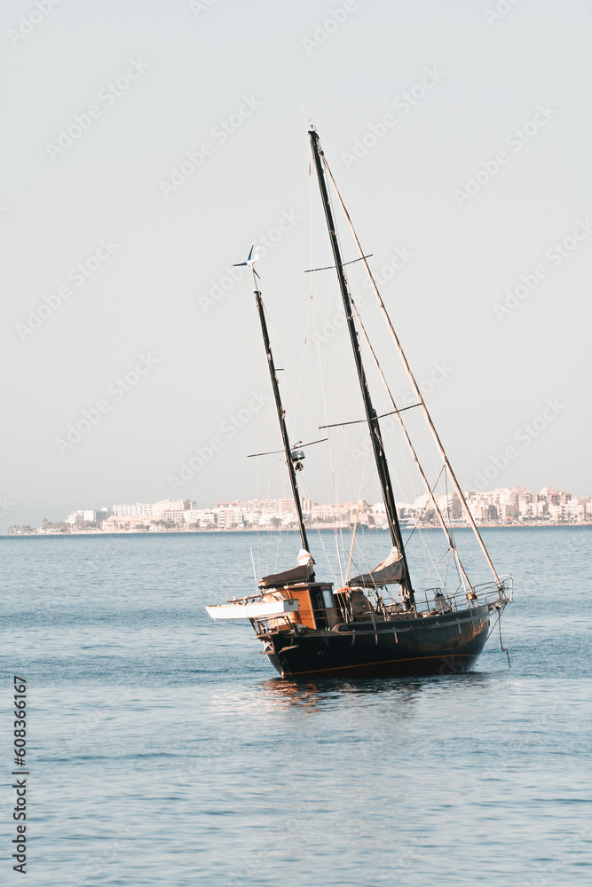 two-masted sailing vessel at anchor off the coast of the sea