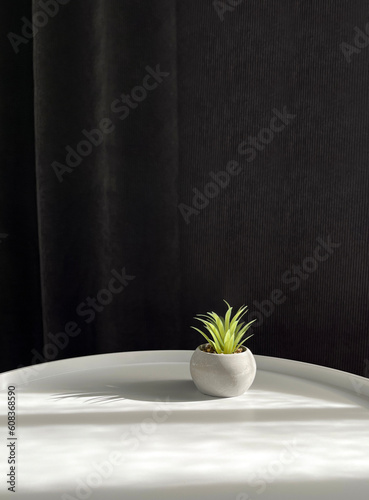 An artificial succulent vase in a concrete pot on a white table on a gray fabric background