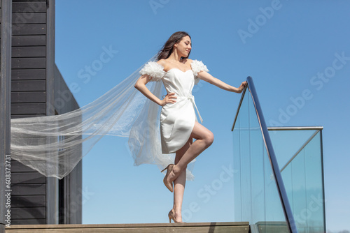 Beautiful bride in white wedding dress posing on the stairs of the hotel