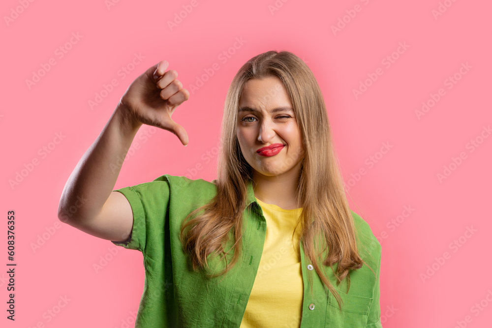 Pretty woman with sign of dislike. Young millennial girl showing thumbs-down Pretty woman with sign of dislike. Young millennial girl showing thumbs-down