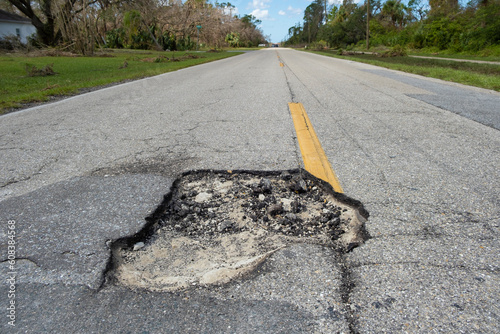 Dangerous pothole on american road surface. Ruined driveway in urgent need of repair