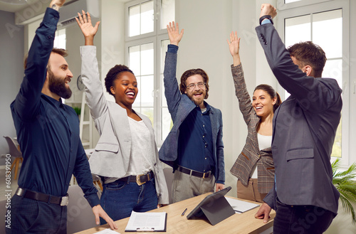 Quadro em tela Friendly personnel men and women raise their hands with smile voting for choice of new project or choosing company marketing strategy stand in modern office around table