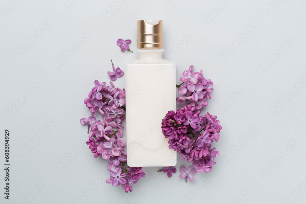 Composition with cosmetic bottle and flowers on color background, top view Composition with cosmetic bottle and flowers on color background, top view