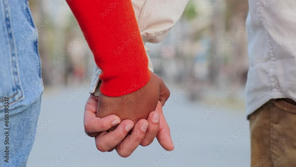Close up slow motion of a young multiracial couple walking together and holding hands with affection. Union of married pair of people bonding on a tender and amorous relationship on a romantic dating