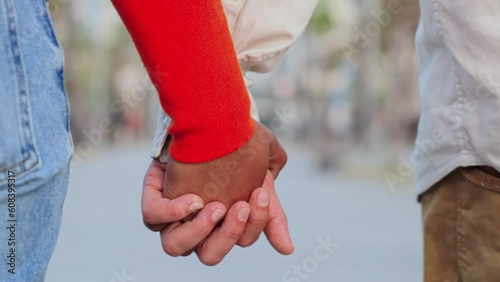 Close up slow motion of a young multiracial couple walking together and holding hands with affection. Union of married pair of people bonding on a tender and amorous relationship on a romantic dating