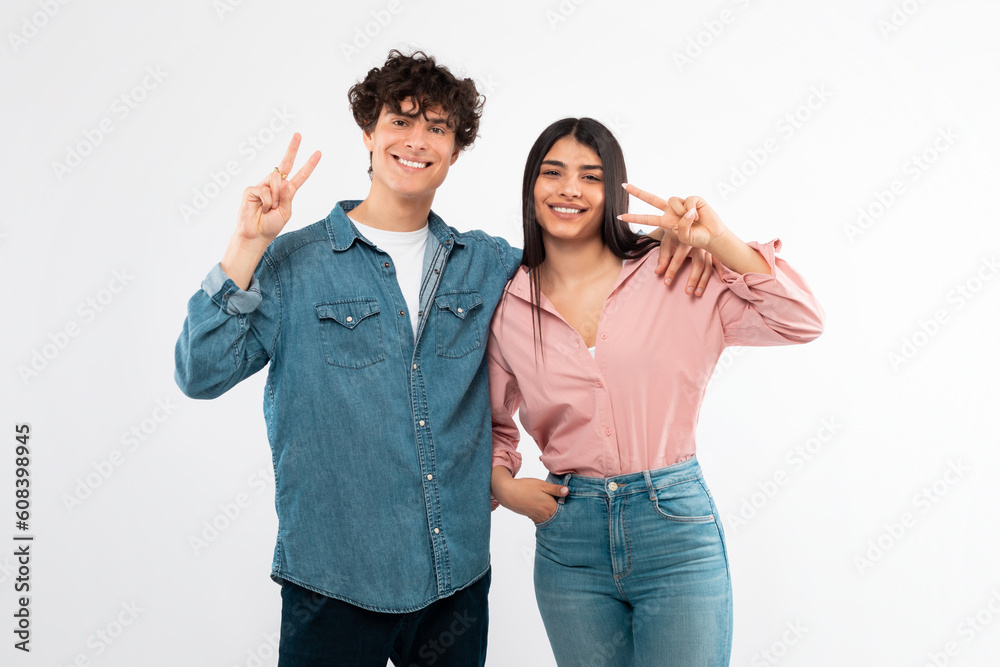 Happy Young Couple Posing Gesturing Victory Sign Over White Background Happy Young Couple Posing Gesturing Victory Sign Over White Background