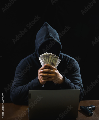 Hacker spy man wearing a black shirt, sitting on a chair and a table, is a thief, hands holding money, counting the amount obtained from hijacking or robbing, in a pitch-black room.