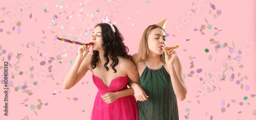 Beautiful young women with party blowers celebrating Birthday on pink background