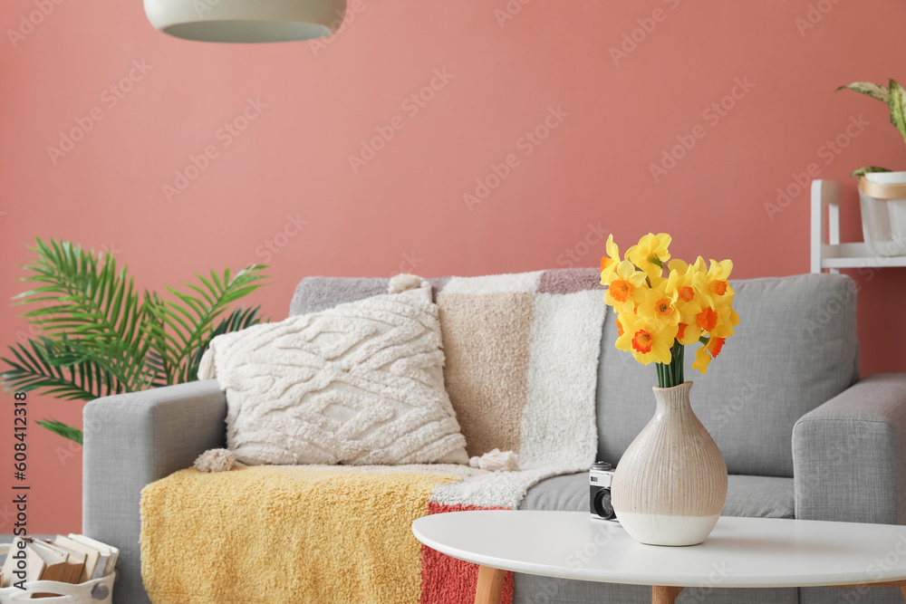 Vase with narcissus flowers on coffee table in interior of stylish living room