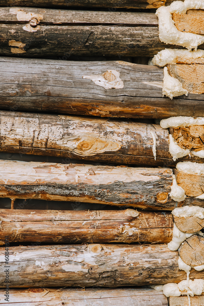 Background, texture of a wall made of wooden logs of pine, coniferous wood with polyurethane foam. Photography, nature. Background, texture of a wall made of wooden logs of pine, coniferous wood with polyurethane foam. Photography, nature.