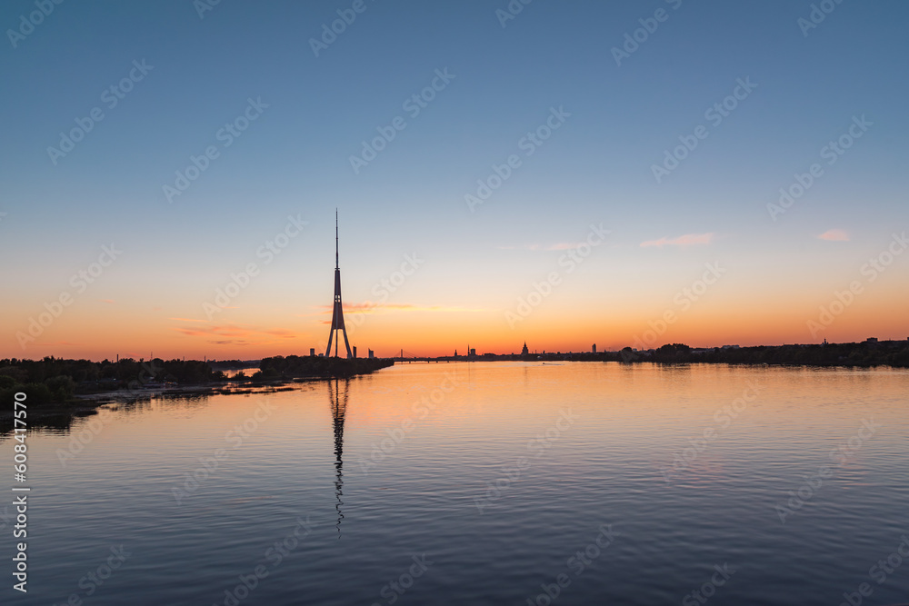Silhouette of Riga panorama with television tower reflecting in Daugava river after the sunset on summer evening