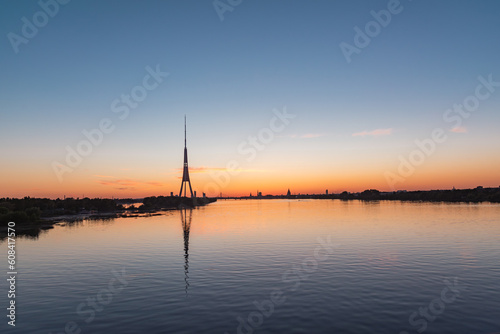 Silhouette of Riga panorama with television tower reflecting in Daugava river after the sunset on summer evening © Julija