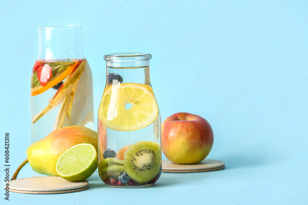 Bottles of infused water with different sliced fruits on blue background Bottles of infused water with different sliced fruits on blue background