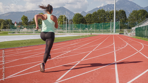 Athlete woman starting to run on the athletic track from the three-point sprint start position © 24K-Production