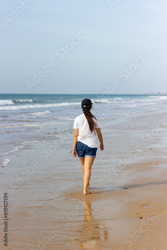 Vacation on the coast. Young woman walking on the beach.