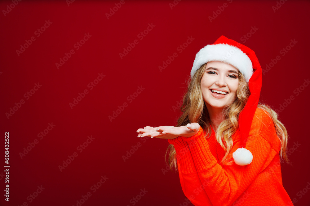 banner. a beautiful woman in a Santa Claus hat points hands to a red background. banner. a beautiful woman in a Santa Claus hat points hands to a red background.
