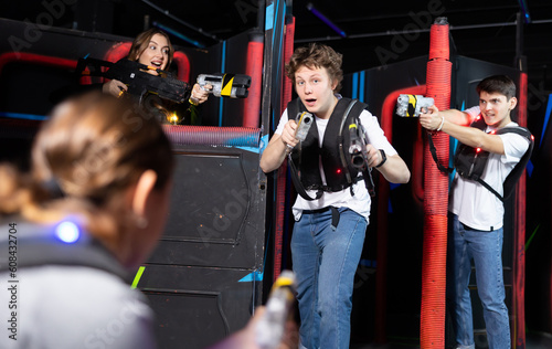 Two guys and one girl running and dodging while playing lasertag © JackF
