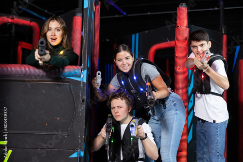 Ordinary Laser tag players young mens and womens playing in teams in dark laser tag station