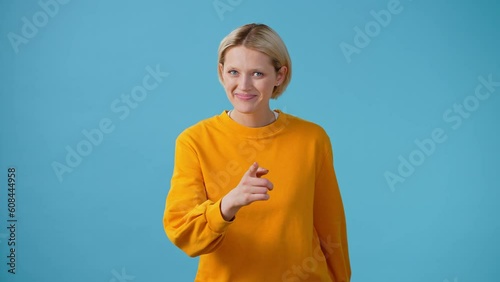 Smiling woman points finger and makes heart shape with hands
