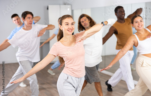 Group of sporty young adult multinational sports people making straight line with hands exercising dancing in gym