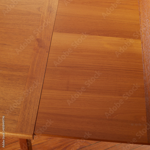 Mid-century modern teak draw leaf table. Close-up detail photographed from above highlighting the table leaf with a wood grain texture.