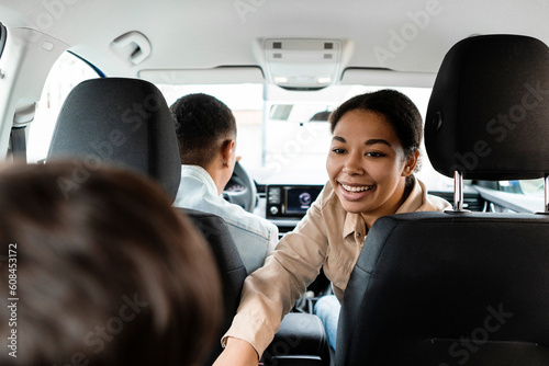 Vászonkép Back view of happy black family riding car, mother talking to child, father, mom