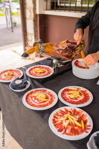 Detail of a man cutting Iberian ham at a wedding or event. Service of a person cutting a piece of ham. Cook or cutter with a knife. traditional food of spain