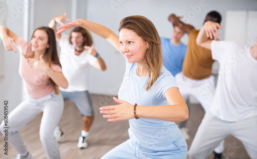 Portrait of cheerful female training position of hands before pair dance in modern fitness studio