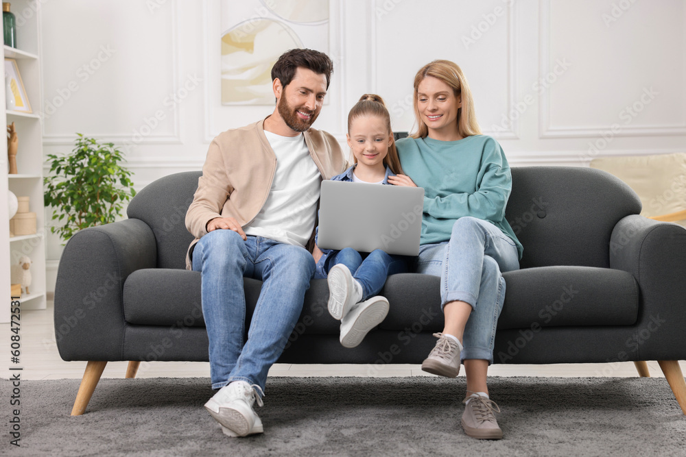 Happy family spending time together and using laptop on sofa at home