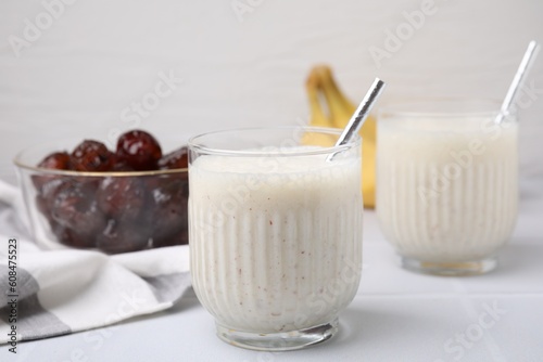 Glasses of delicious date smoothie with straws on white table