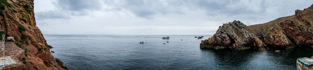 Panoramic view of the coast of the Berlenga Islands in the Atlantic Ocean of Portugal. Cloudy landscape of the Iberian Peninsula. Fishing boats in the water. Panoramic view of the coast of the Berlenga Islands in the Atlantic Ocean of Portugal. Cloudy landscape of the Iberian Peninsula. Fishing boats in the water.