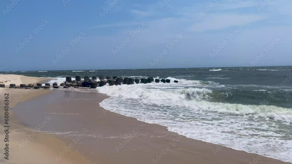 Looking east on the beach on Fire Island at storm waves crashing on to the shore and a jetty. Looking east on the beach on Fire Island at storm waves crashing on to the shore and a jetty.